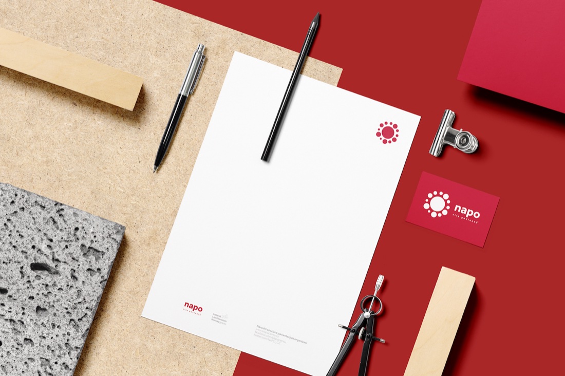 NAPO brand stationery — letterhead and business cards with the flower logo, on a crimson flat-lay