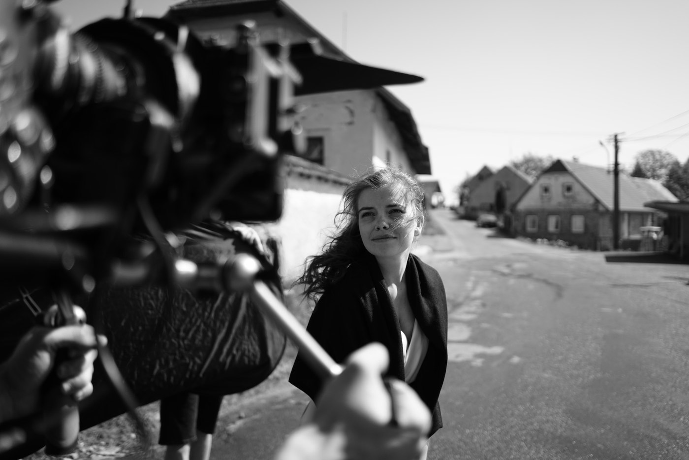 Behind-the-scenes photo of the actress on a village street, the camera rig in the foreground