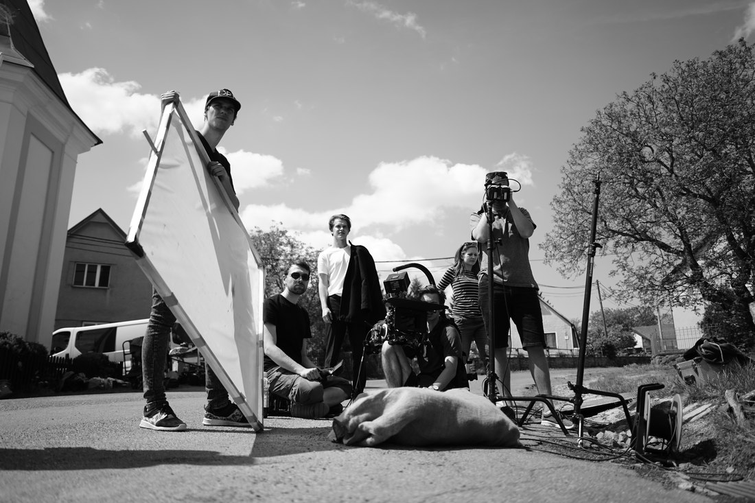 The full film crew posed with camera and lighting equipment on a village street