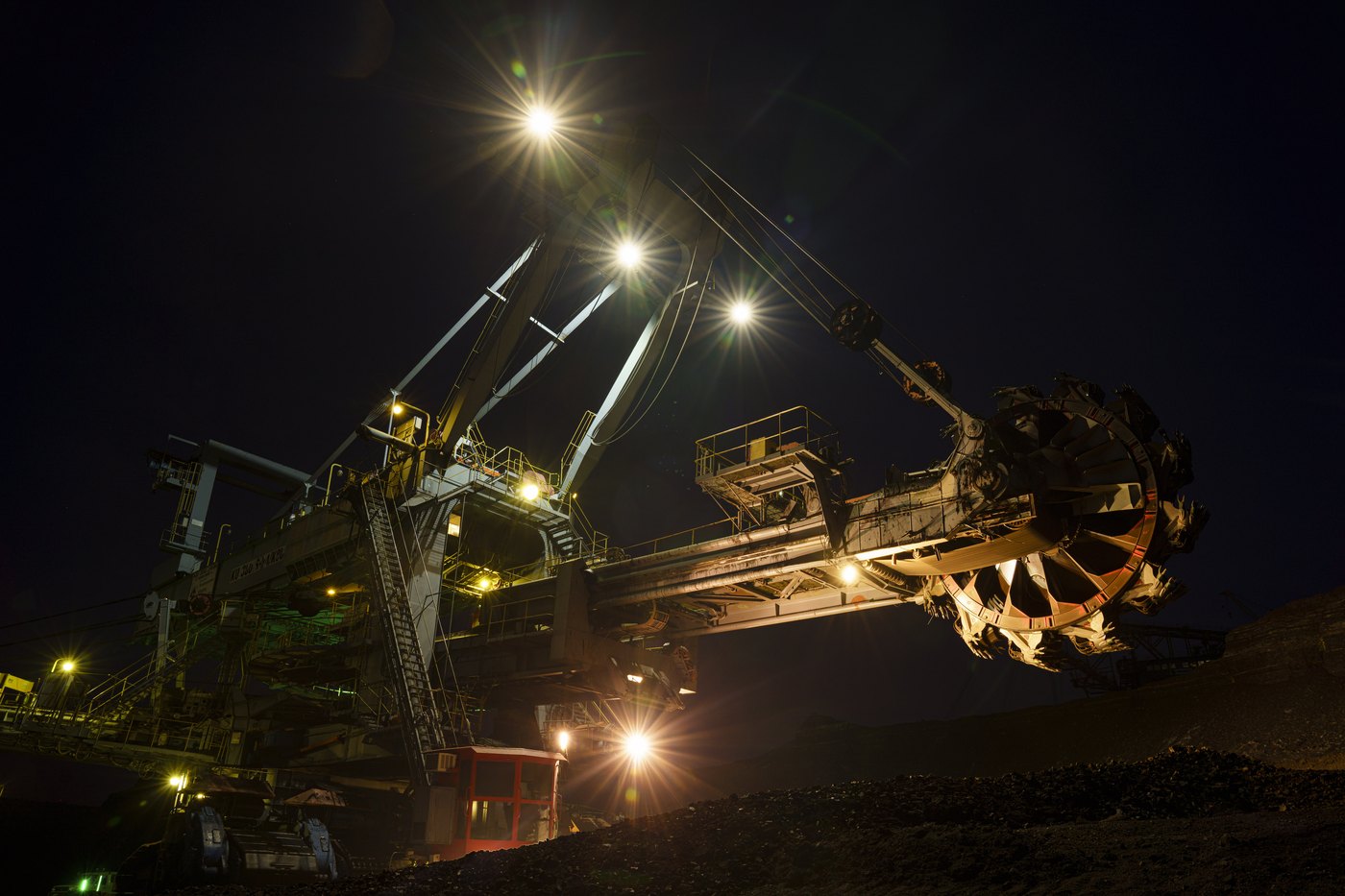 A bucket-wheel excavator lit up at night against a dark sky at the mine