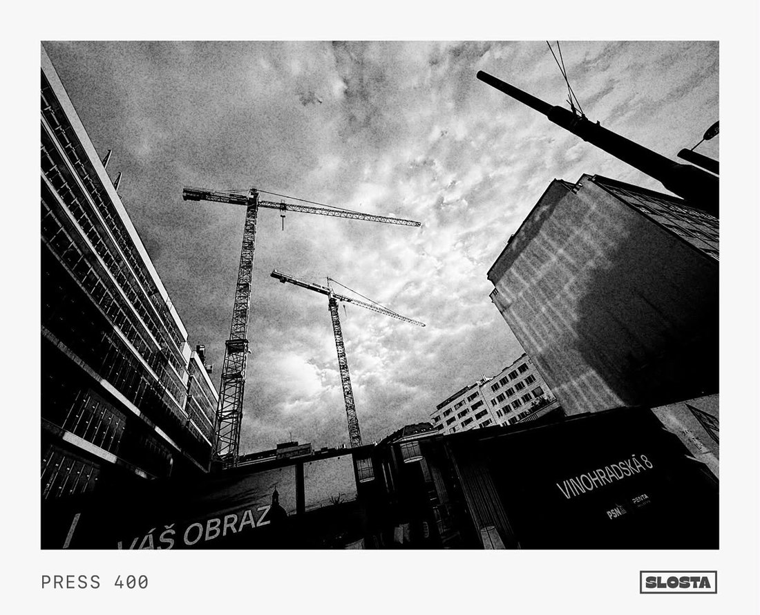 Construction cranes against the sky above a city building, black-and-white film