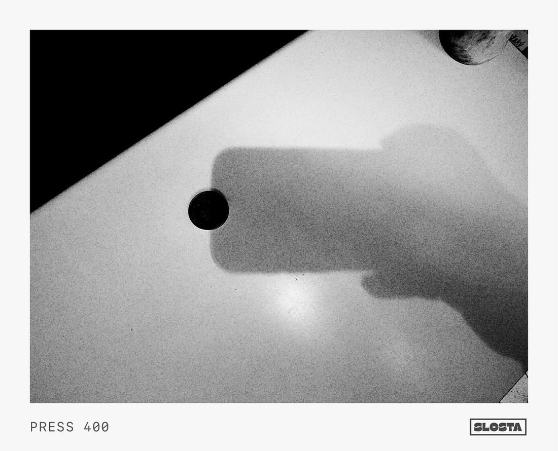A phone's shadow cast on a bright white table, black-and-white film